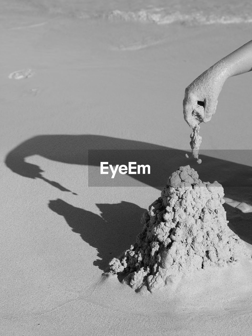 Close-up of hand playing with sand at beach