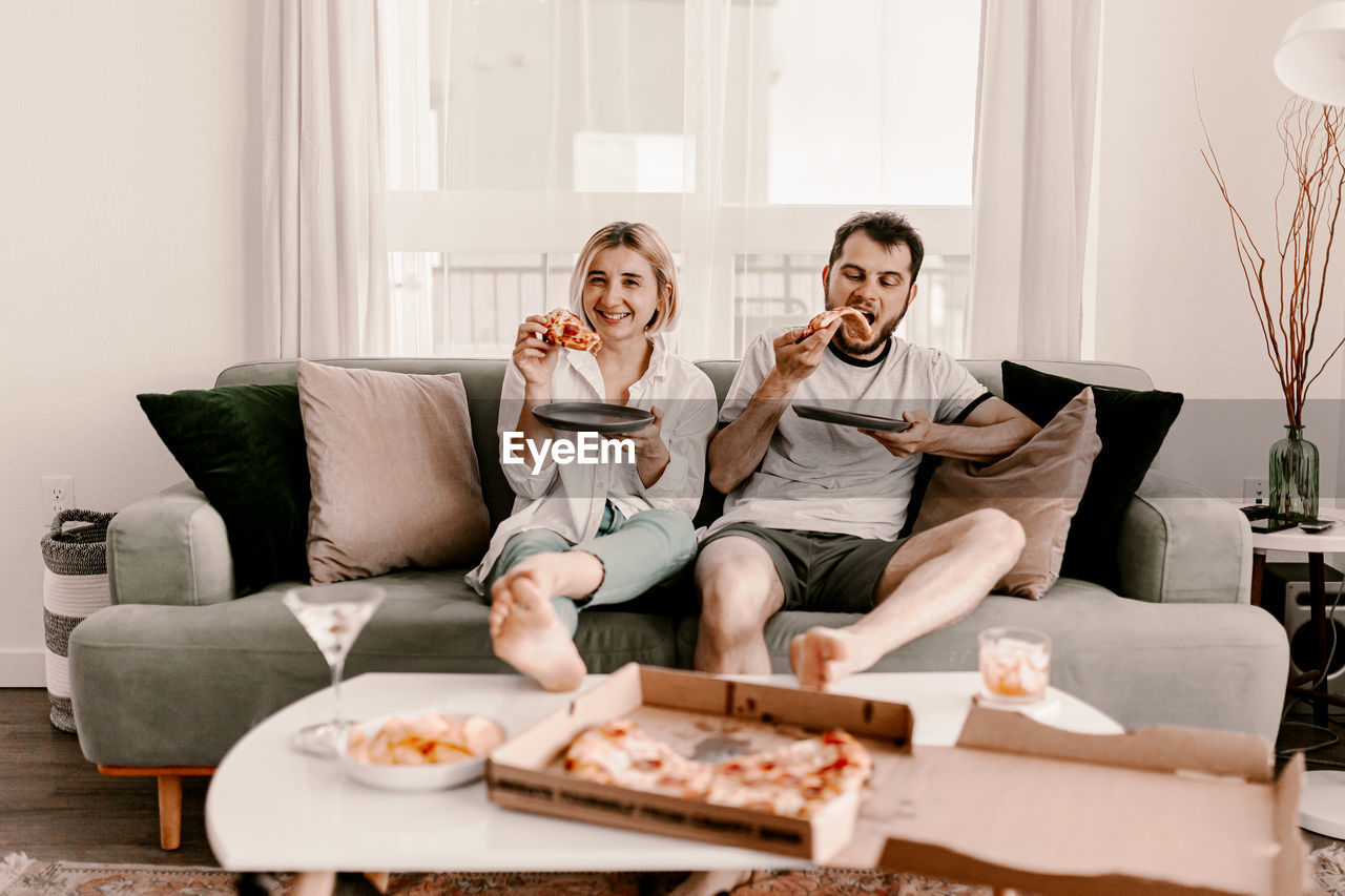 Couple eating pizza while sitting at home
