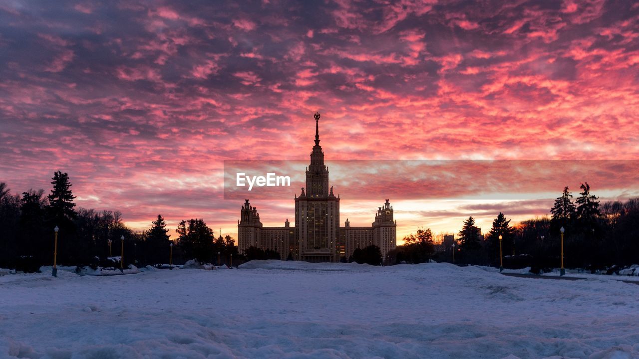 BUILDINGS ON SNOW COVERED FIELD AT SUNSET