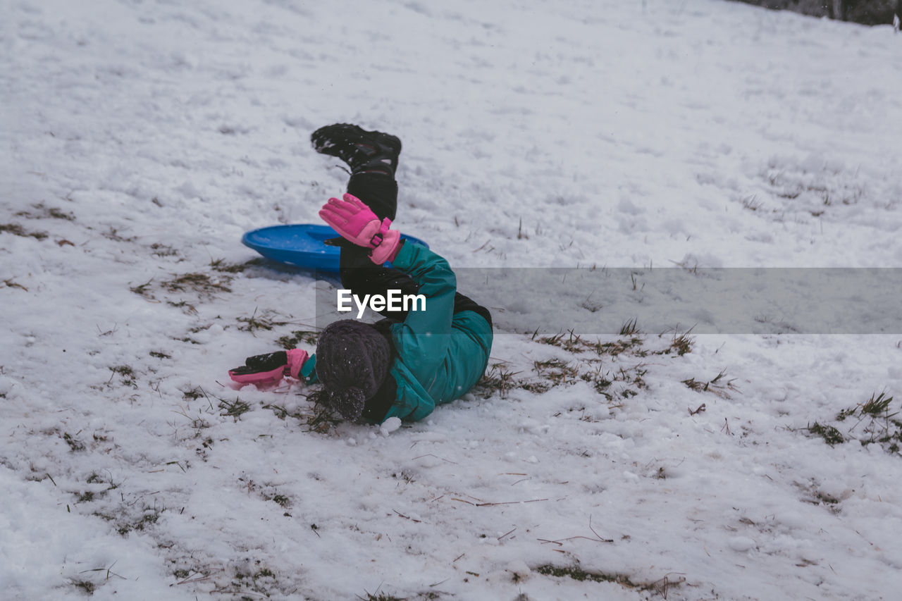 Full length of girl sitting on bobsled in snow