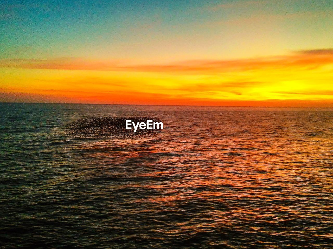 View of sea against cloudy sky at sunset