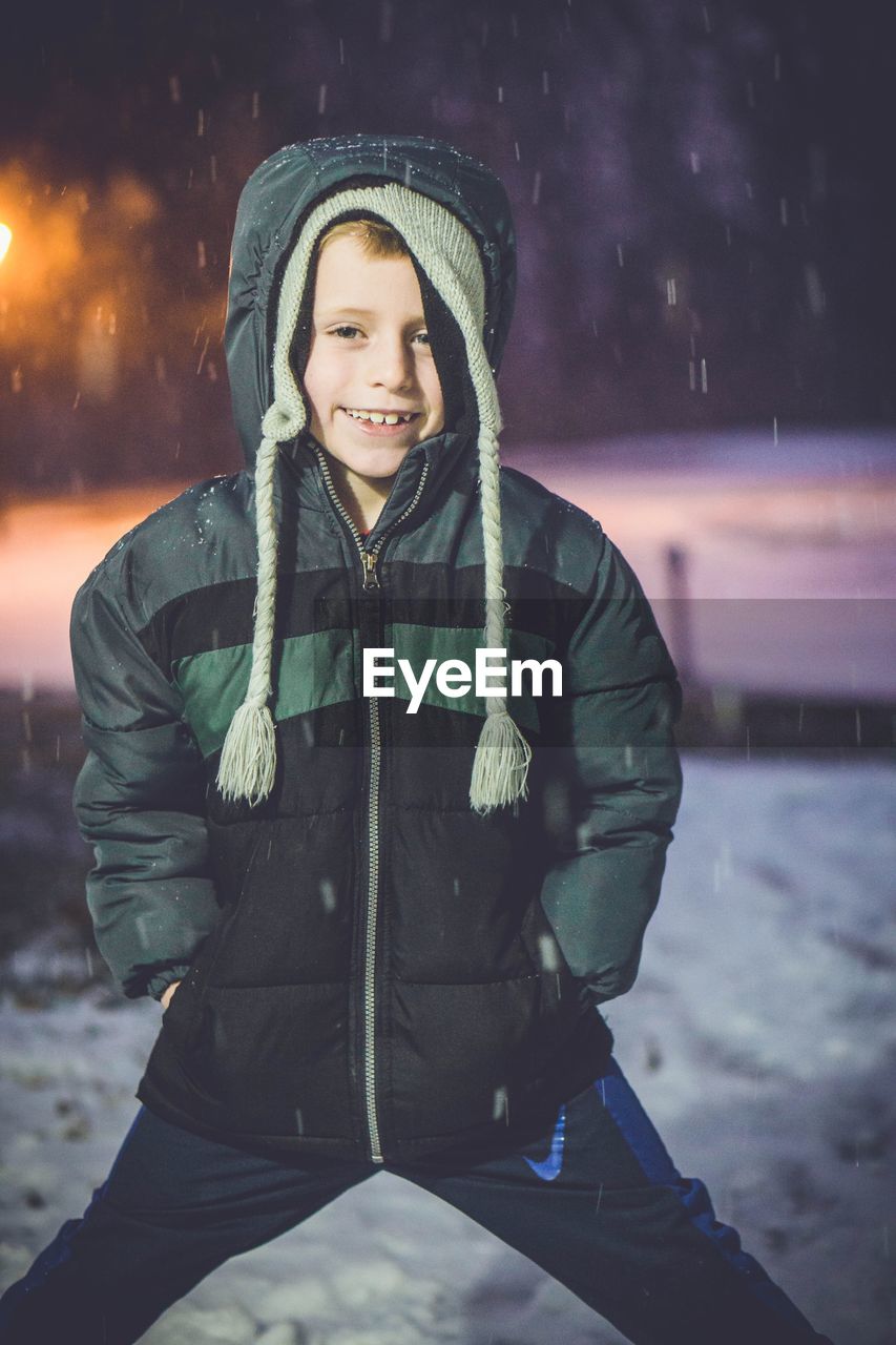 PORTRAIT OF SMILING BOY STANDING IN SNOW