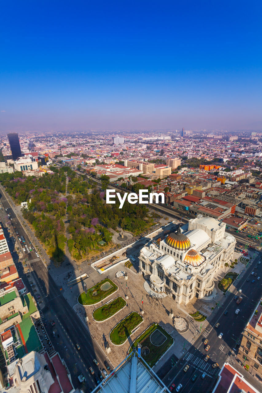 HIGH ANGLE VIEW OF BUILDINGS IN CITY AGAINST BLUE SKY