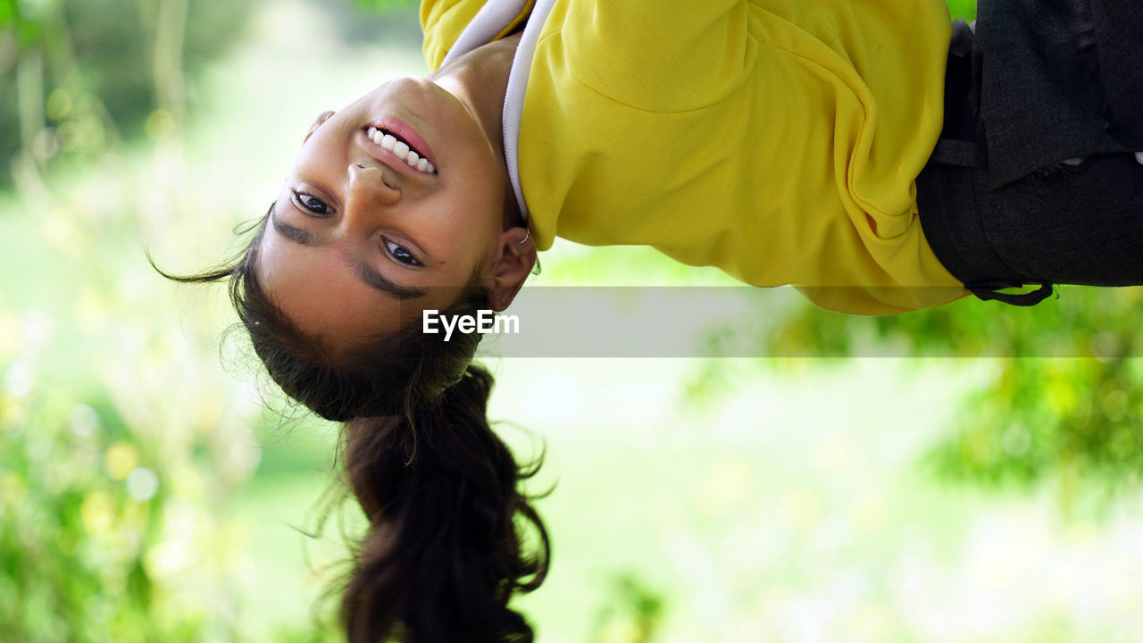 Happy smiling girl hanging on a tree. the child laughs happily. spring mood. active lifestyle.