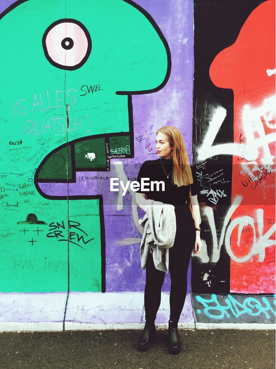 FULL LENGTH OF YOUNG WOMAN STANDING AGAINST GRAFFITI WALL
