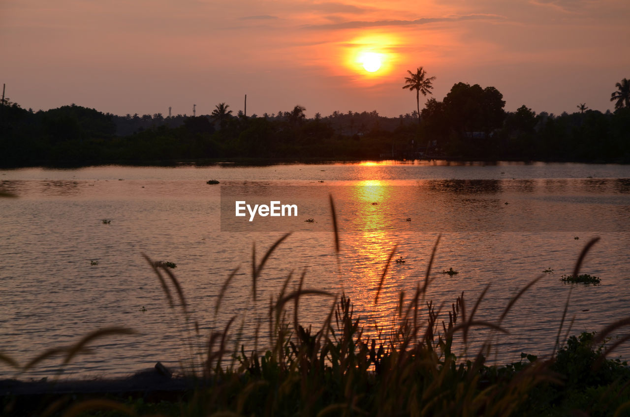 SCENIC VIEW OF LAKE AGAINST SKY AT SUNSET