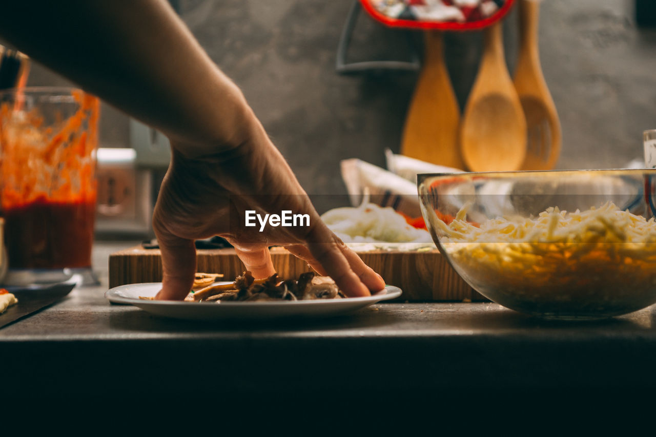 Closeup hand of chef baker in white uniform making pizza at kitchen