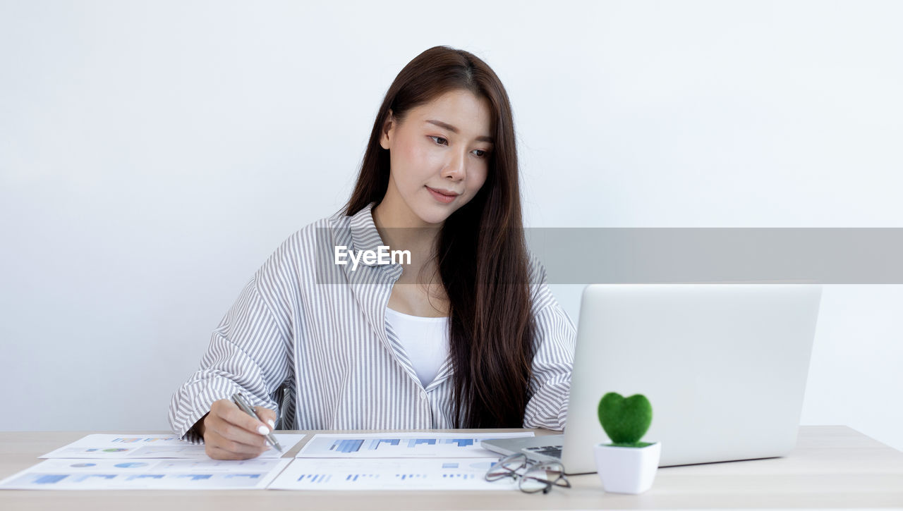 PORTRAIT OF YOUNG WOMAN USING PHONE ON TABLE