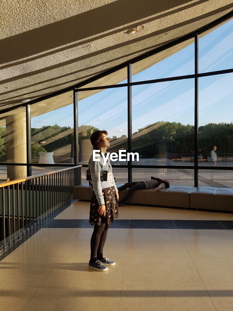 YOUNG WOMAN STANDING BY RAILING AGAINST SKY