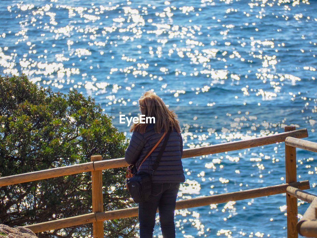 Woman standing by railing against sea