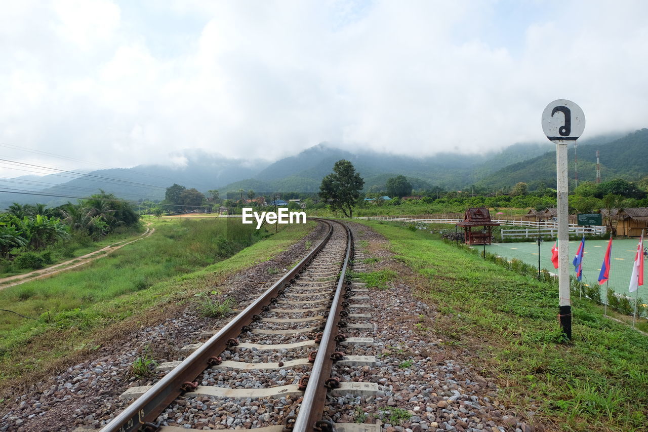 RAILROAD TRACKS BY TREES AGAINST SKY