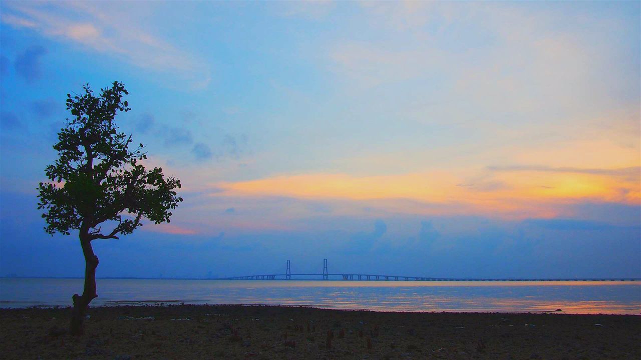 Distant view of bridge over sea against sky during sunset