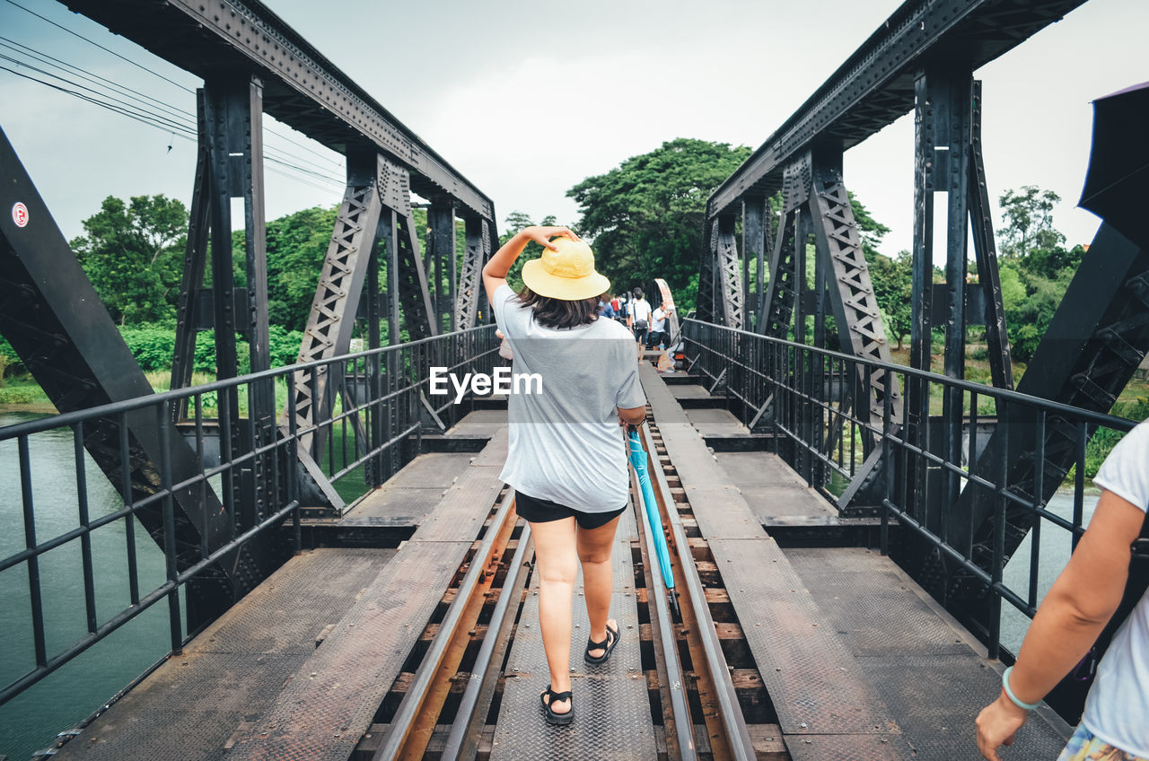 Rear view of woman walking on railroad tracks