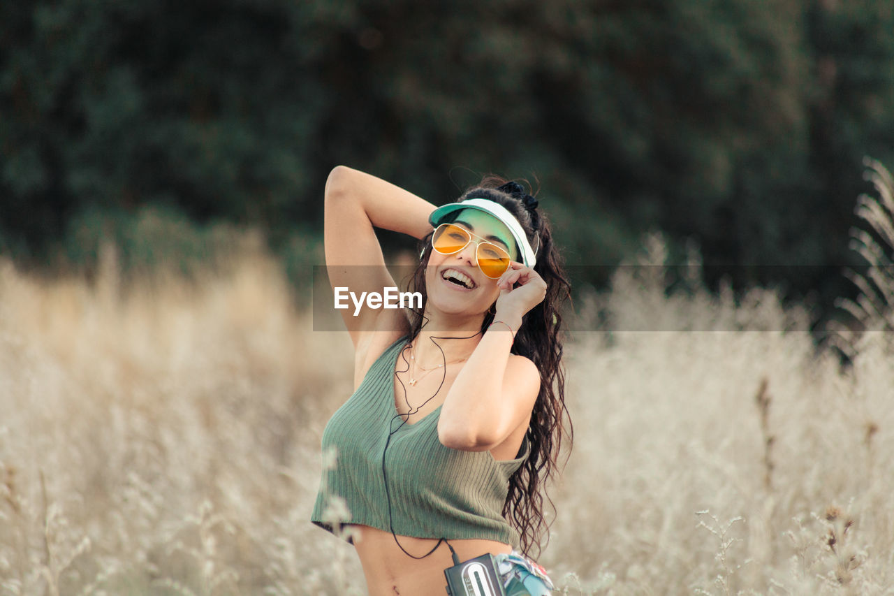 YOUNG WOMAN WEARING SUNGLASSES ON FIELD