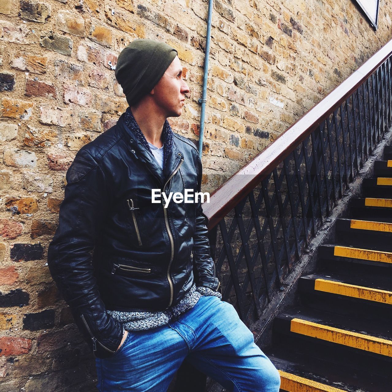Young man in leather jacket standing by stairs