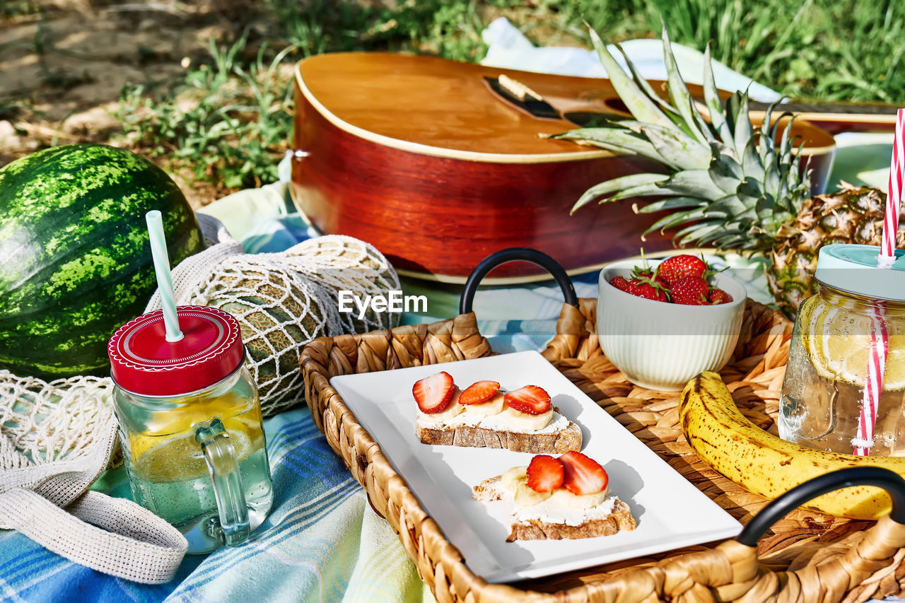 Summertime healthy picnic. fresh tropical fruit, sweet stawberry sandwiches and refreshing drink