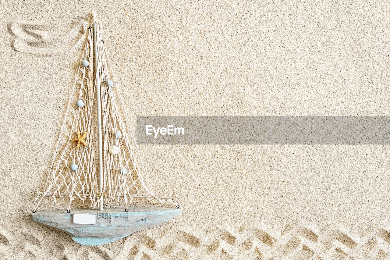 Sand background with small wooden boat, top view, copy space