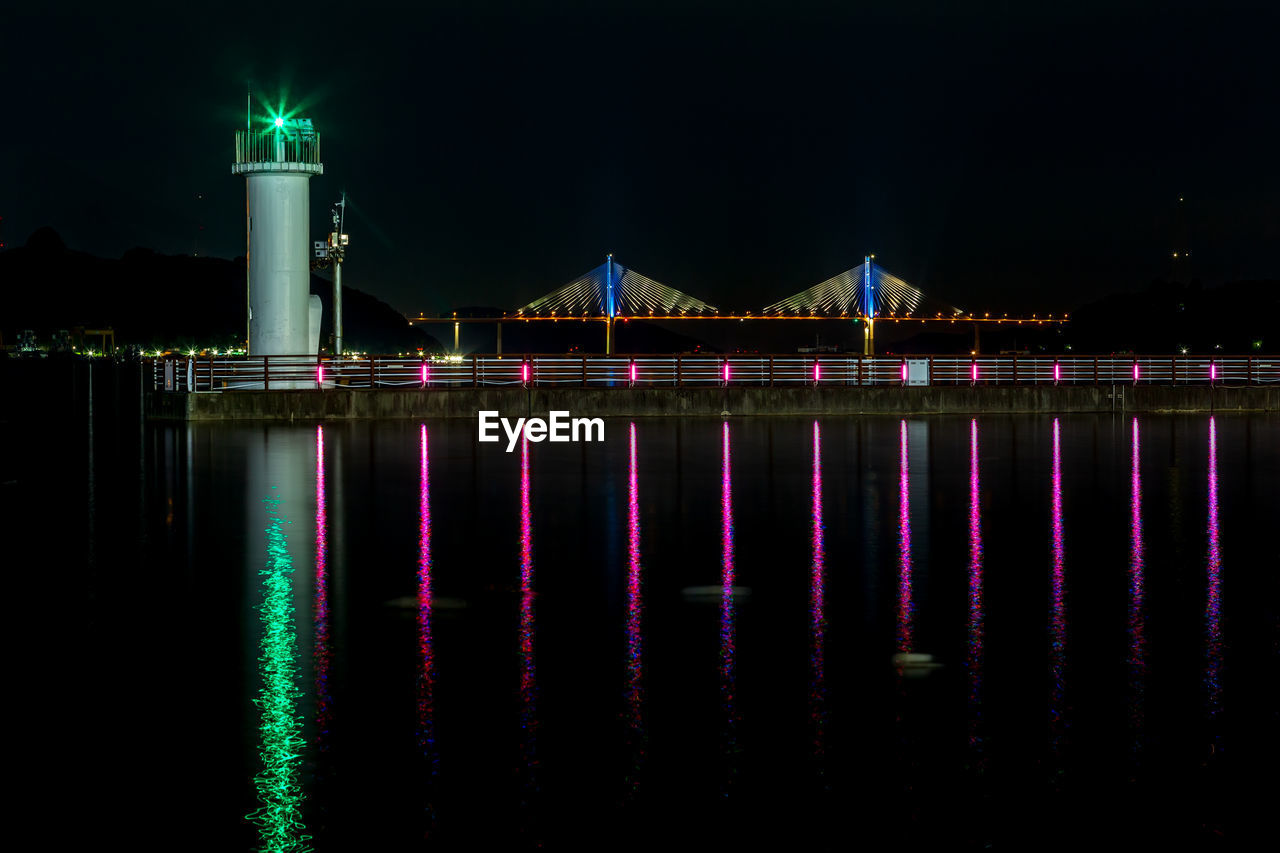 illuminated bridge over river against sky at night