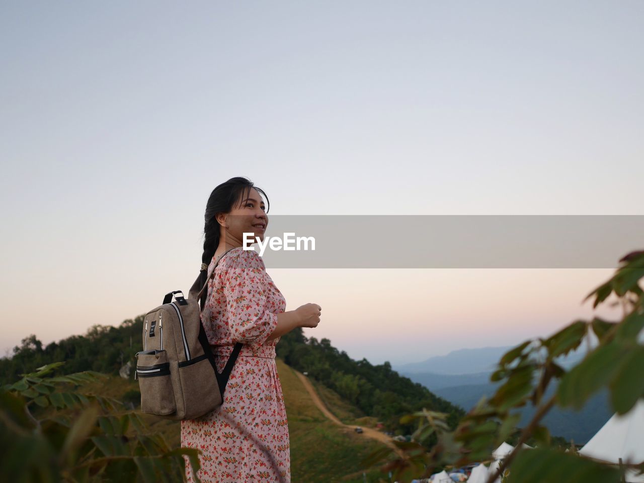 Side view of woman standing on mountain against sky