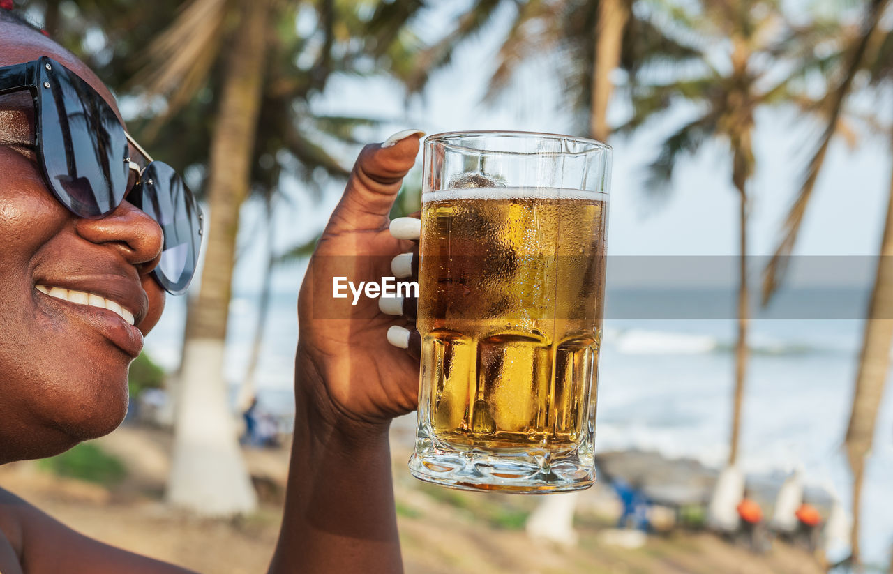 African happy woman drinking a beer out at a beach bar in accra ghana