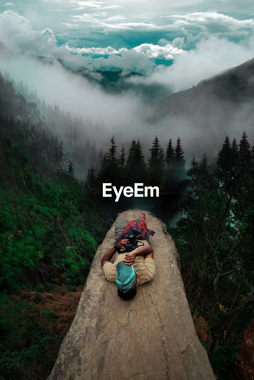 Full length of man lying on tree trunk in forest