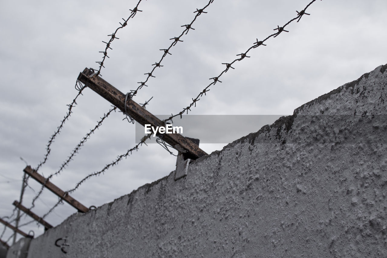 Low angle view of barbed wire against sky