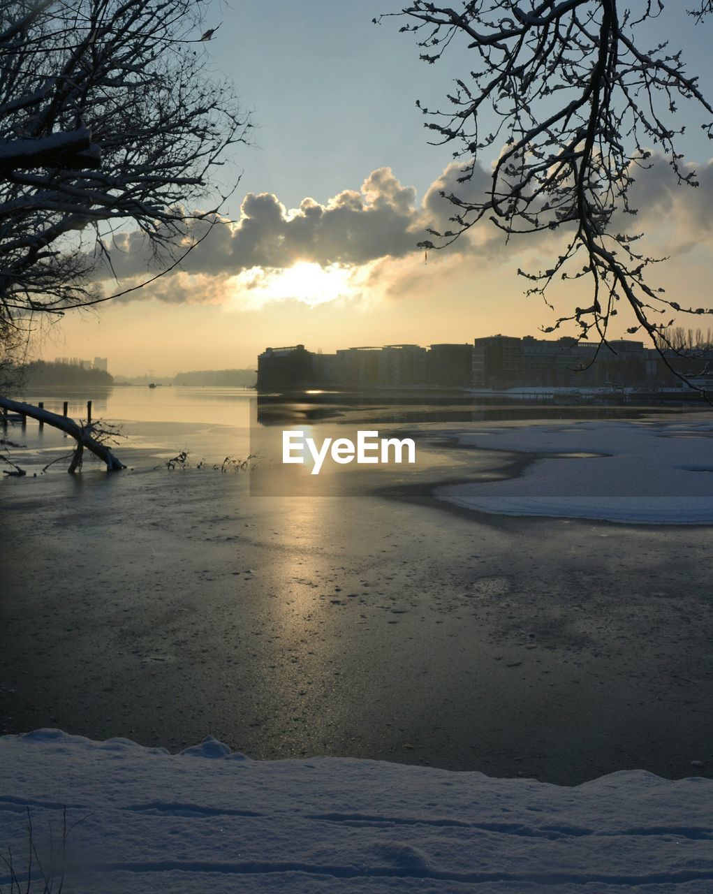 Scenic view of river against sky at sunset during winter