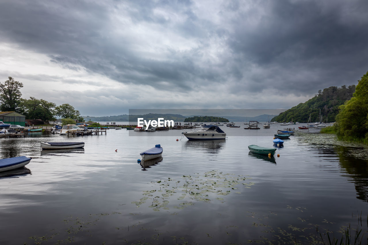 Canoes and motorboats in the beautiful loch loch lomond on a very cloudy day in june, scotland