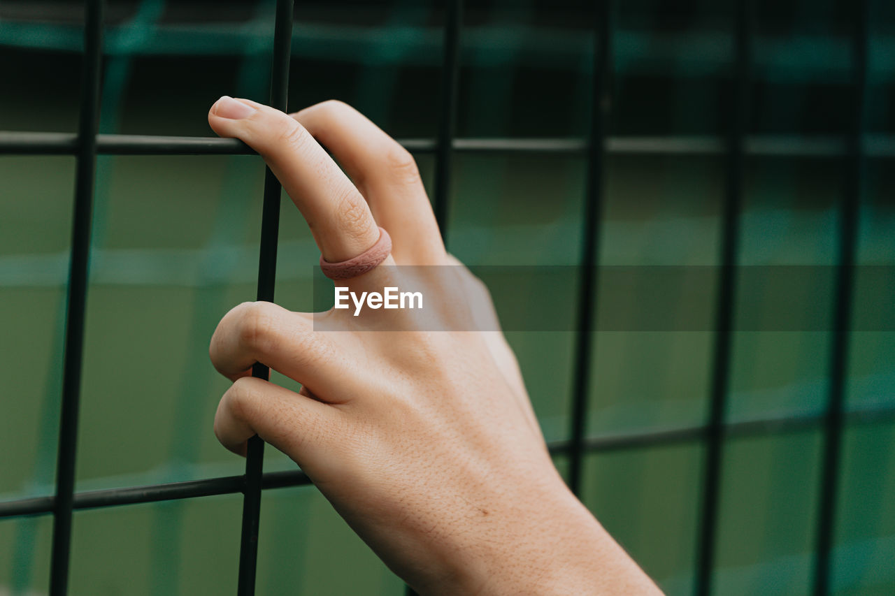 Cropped hand of woman holding fence