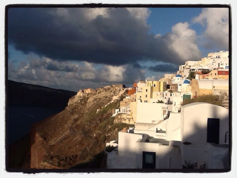 Houses on mountain against cloudy sky