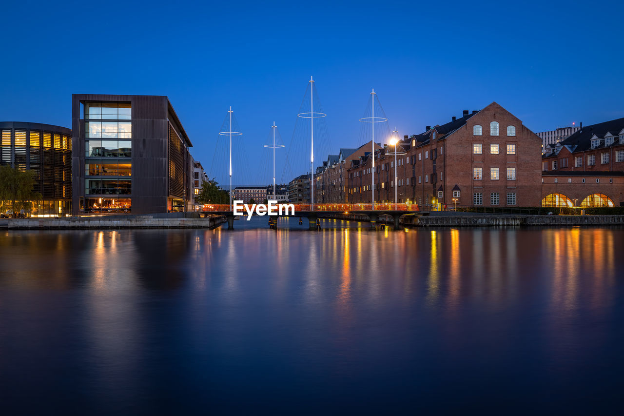 Full moon rising over old packhouses and the new circle bridge in central copenhagen