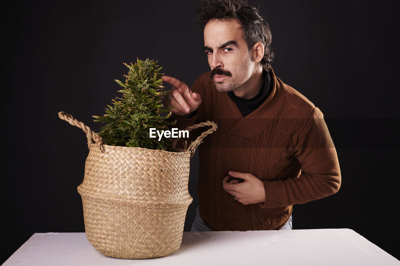 one person, adult, men, person, studio shot, indoors, black background, plant, portrait, container, beard, basket, clothing, flowerpot, nature, facial hair, food and drink, young adult, looking, holding, lifestyles