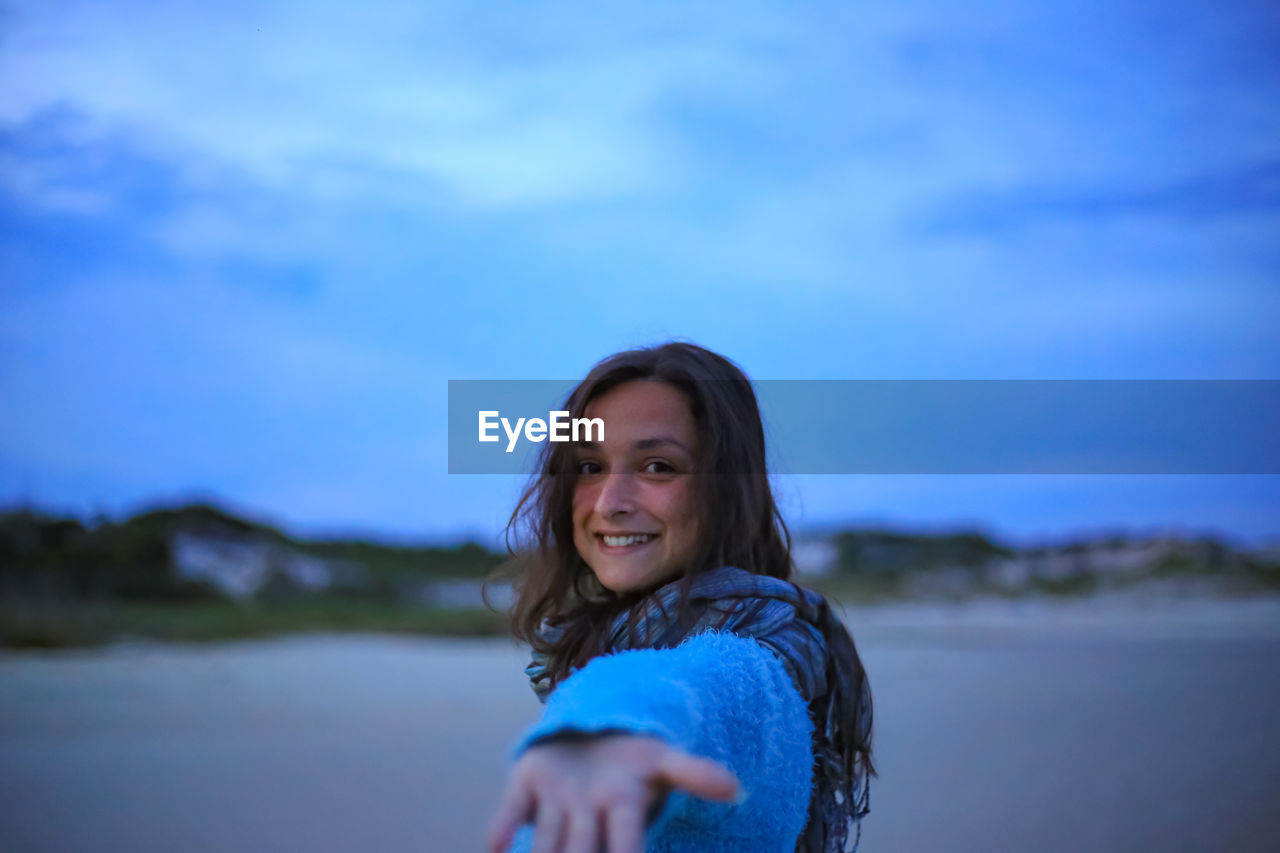 Portrait of smiling woman against blue sky