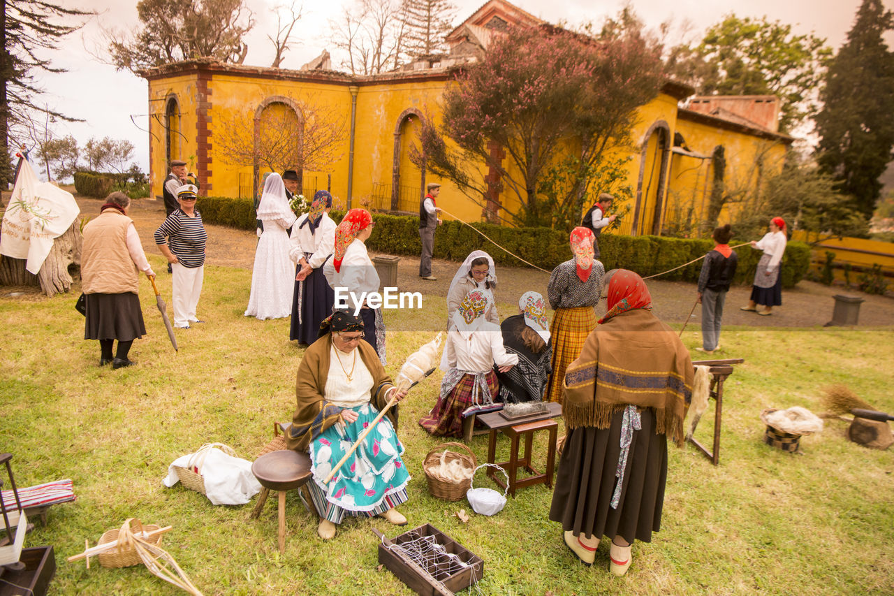 GROUP OF PEOPLE SITTING IN TRADITIONAL CLOTHING