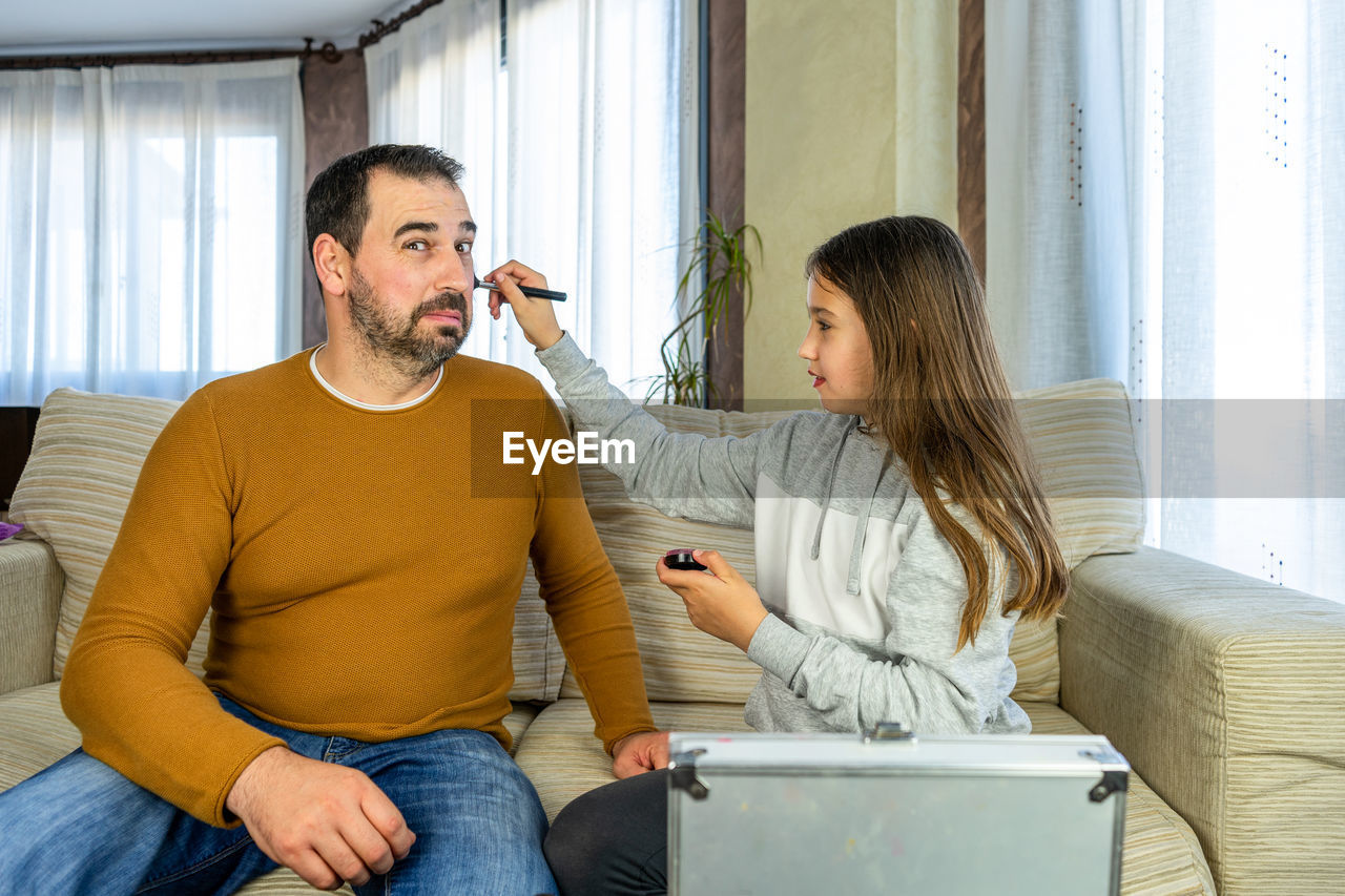 YOUNG COUPLE SITTING ON SOFA AT HOME