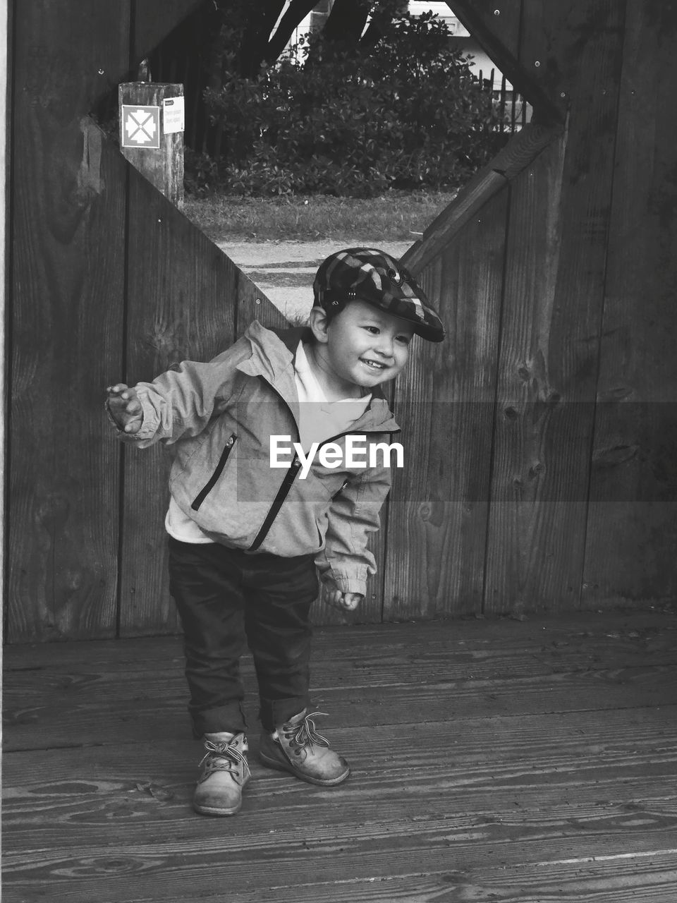 Smiling boy standing against wooden structure