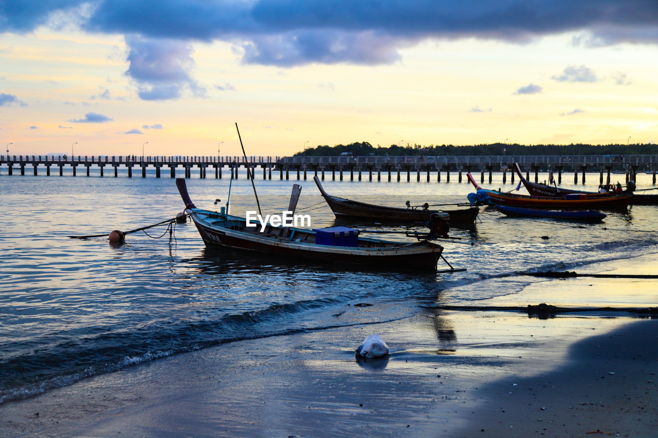 Boats moored in sea at sunset