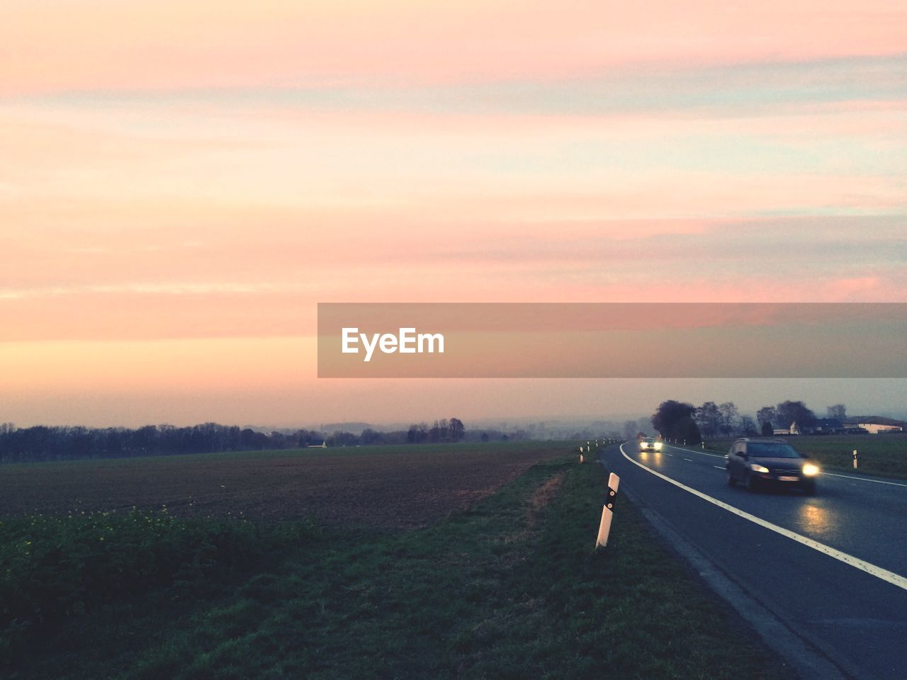 ROAD BY FIELD AGAINST SKY DURING SUNSET