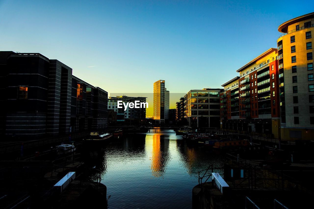 CANAL AMIDST BUILDINGS AGAINST CLEAR SKY