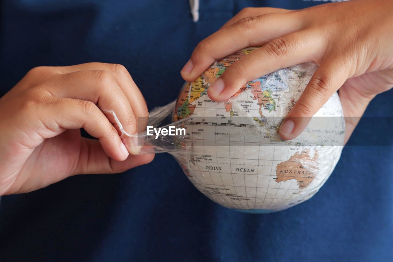 Midsection of person removing plastic on globe