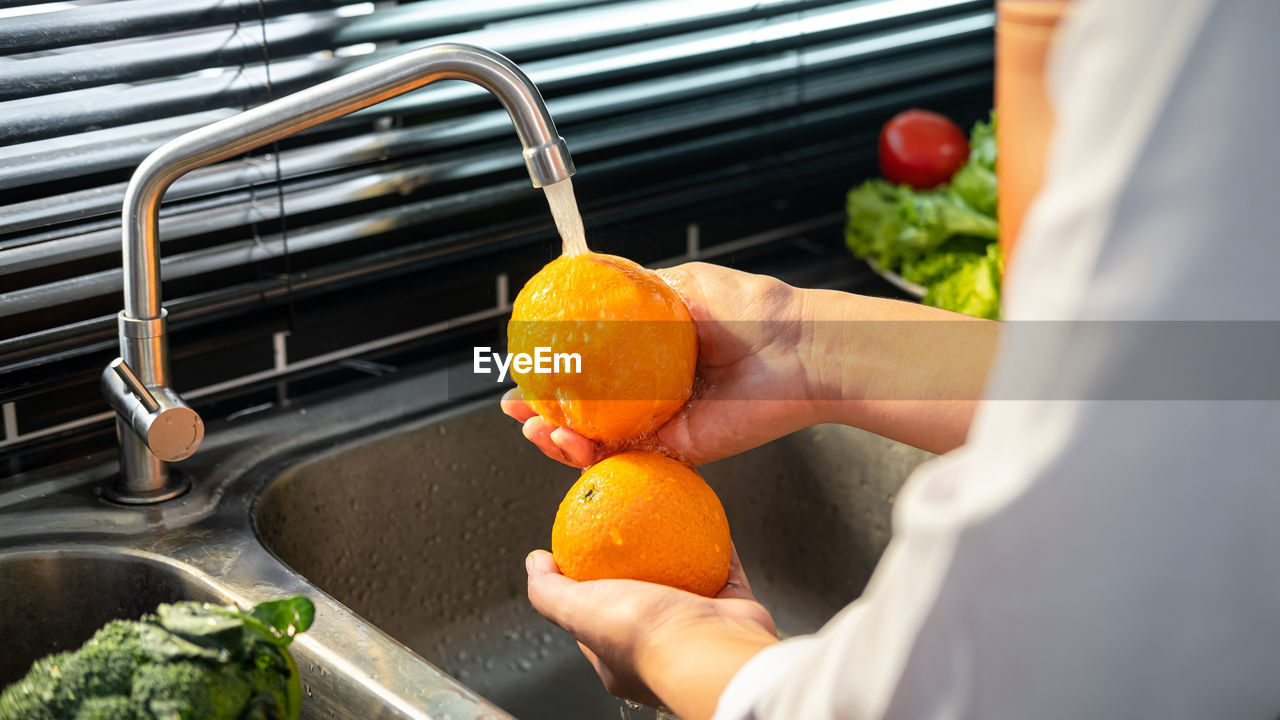 CROPPED IMAGE OF PERSON PREPARING FOOD IN KITCHEN AT HOME