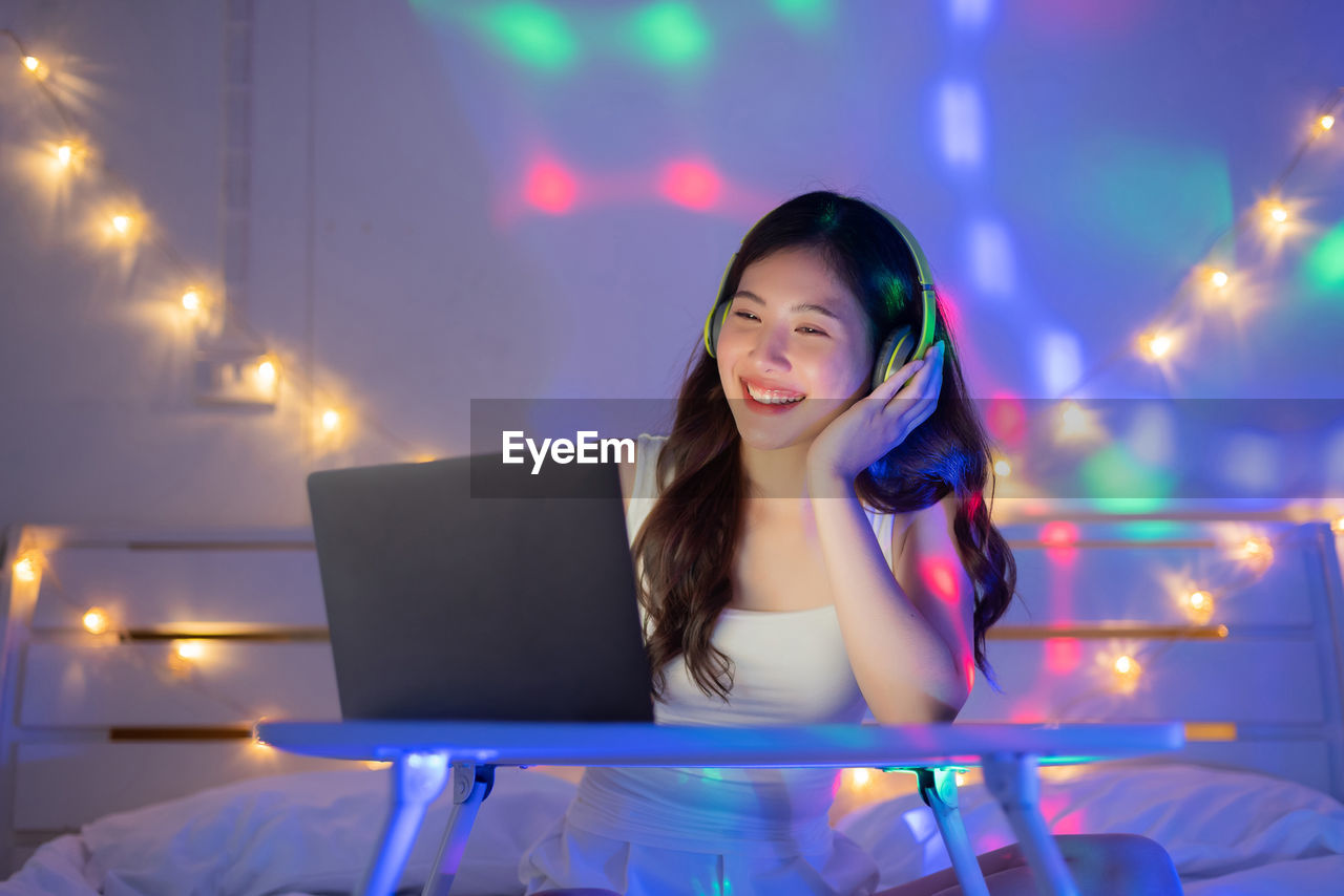 Woman listening to music with laptop on bed in bedroom