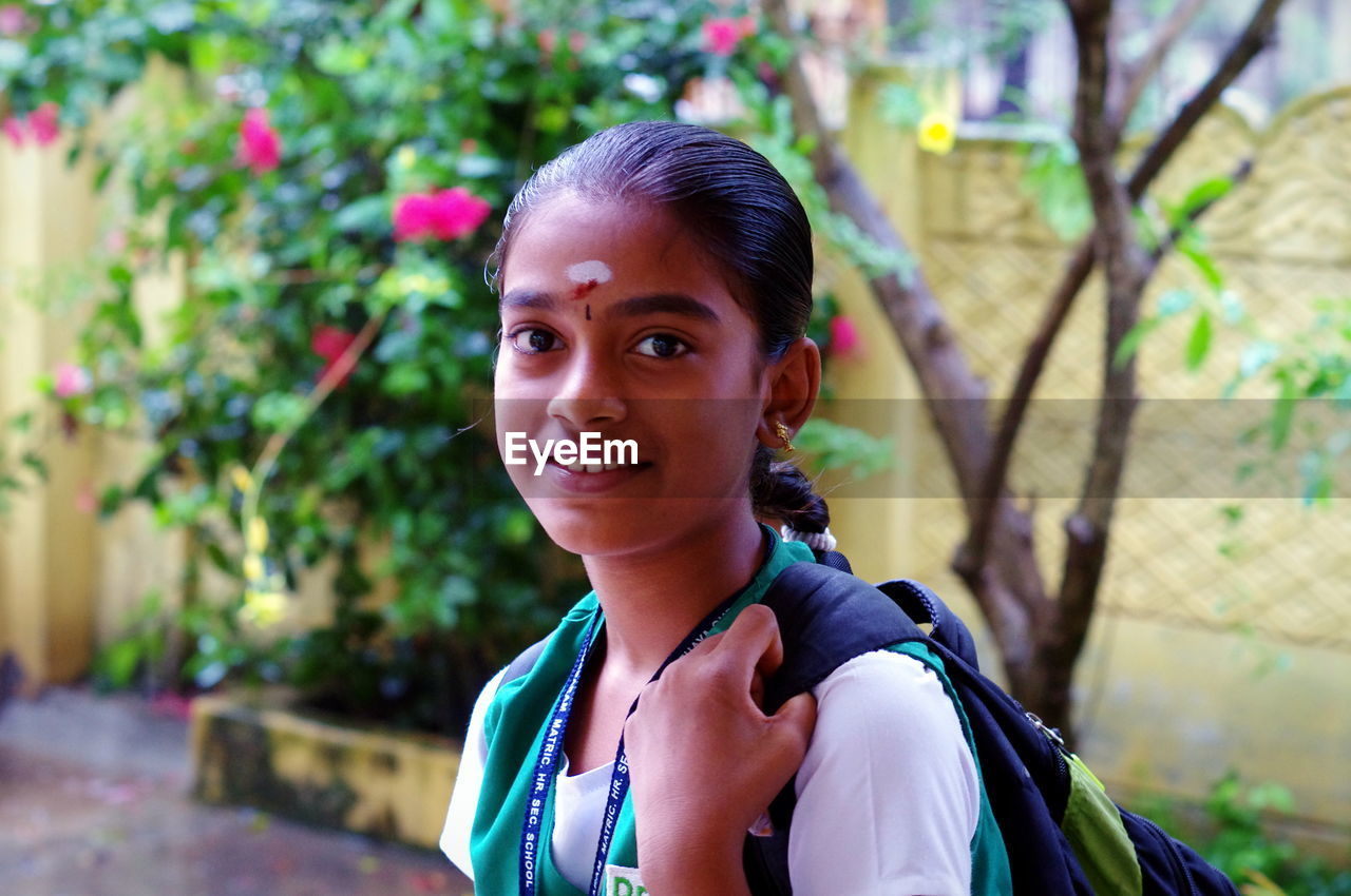 Portrait of smiling girl standing against trees