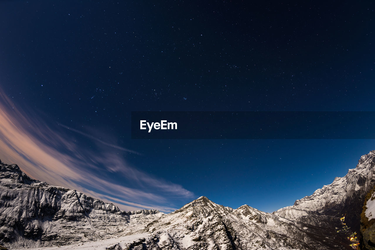 Low angle view of snowcapped mountains against sky at night