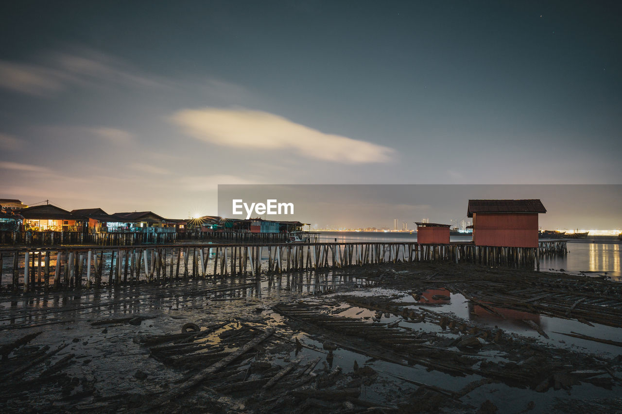 Scenic view of beach by buildings against sky during sunset