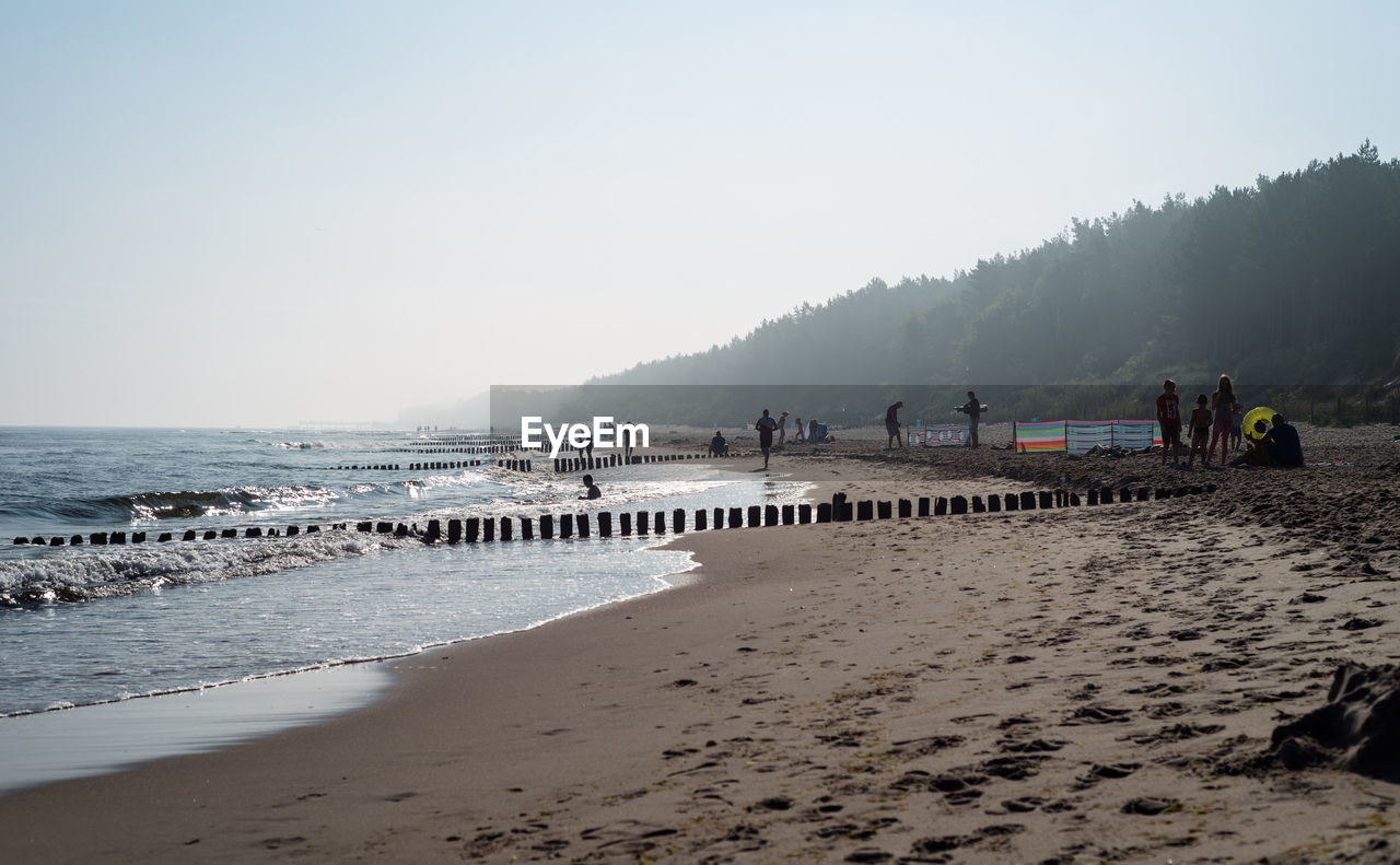 People on beach against clear sky