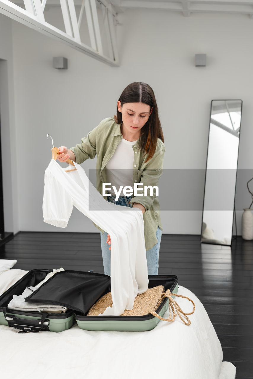 Young brunette woman packing suitcase for a solo traveling abroad. summer vacation. traveling.