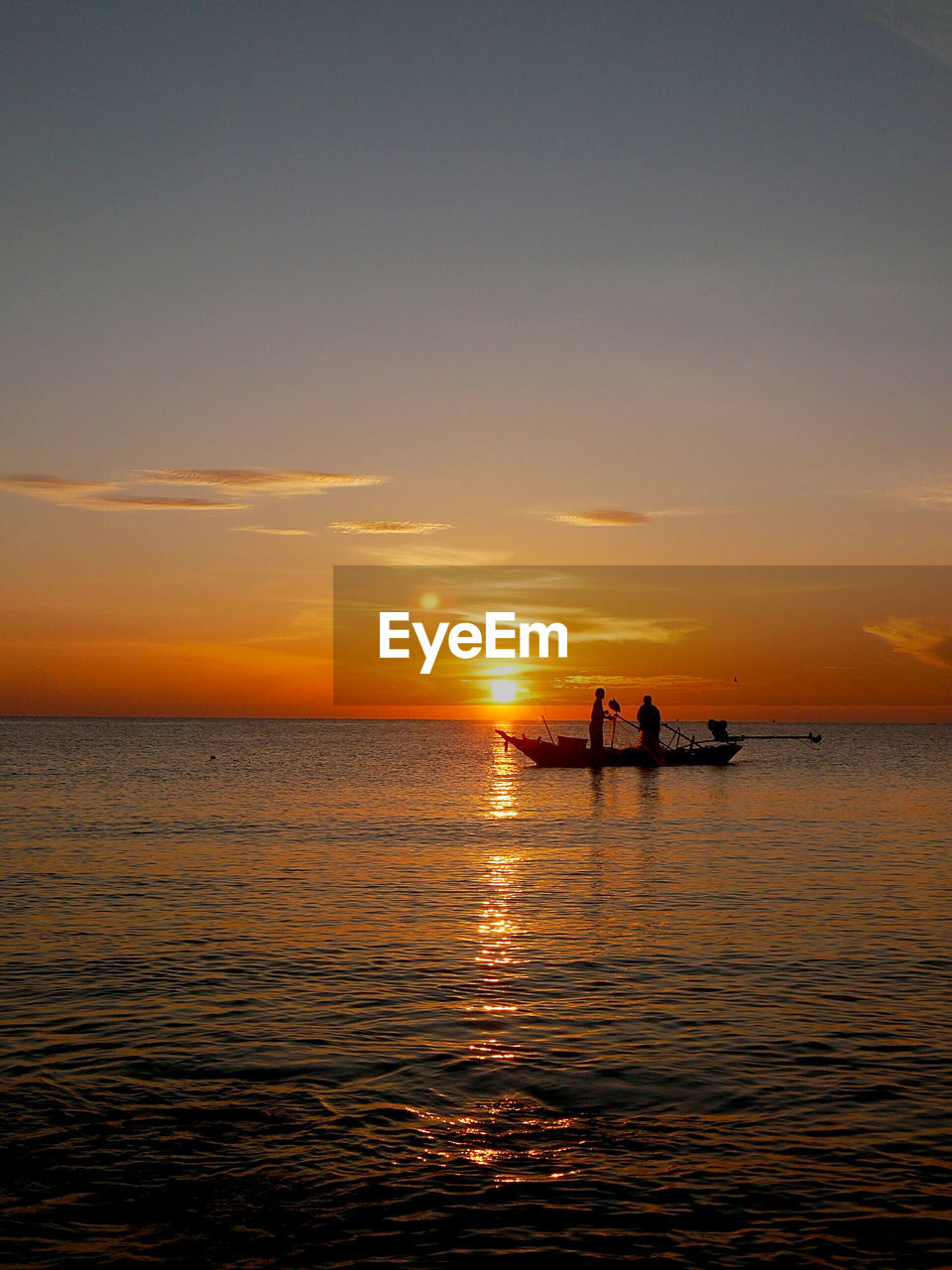 SILHOUETTE PEOPLE IN SEA AGAINST ORANGE SKY