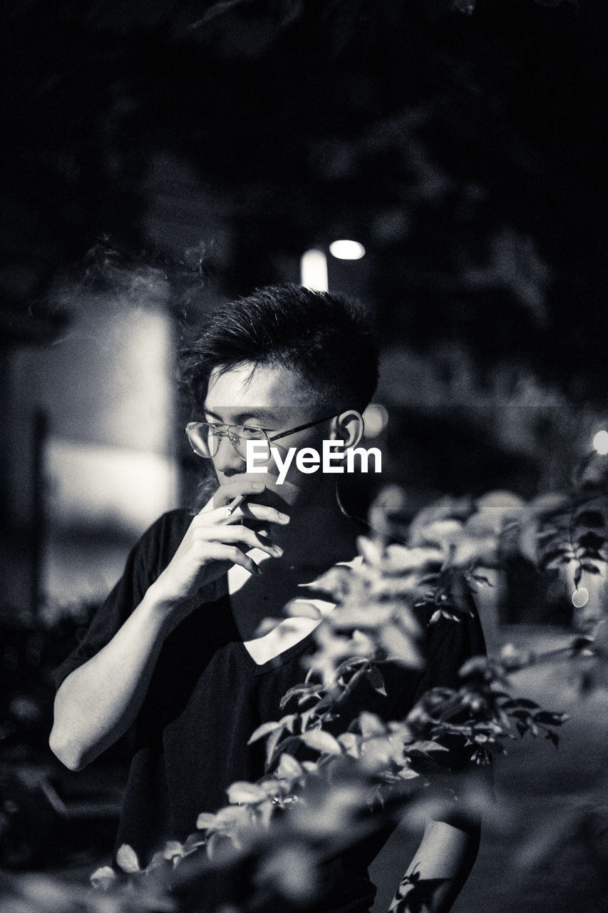 Teenage boy smoking cigarette at night