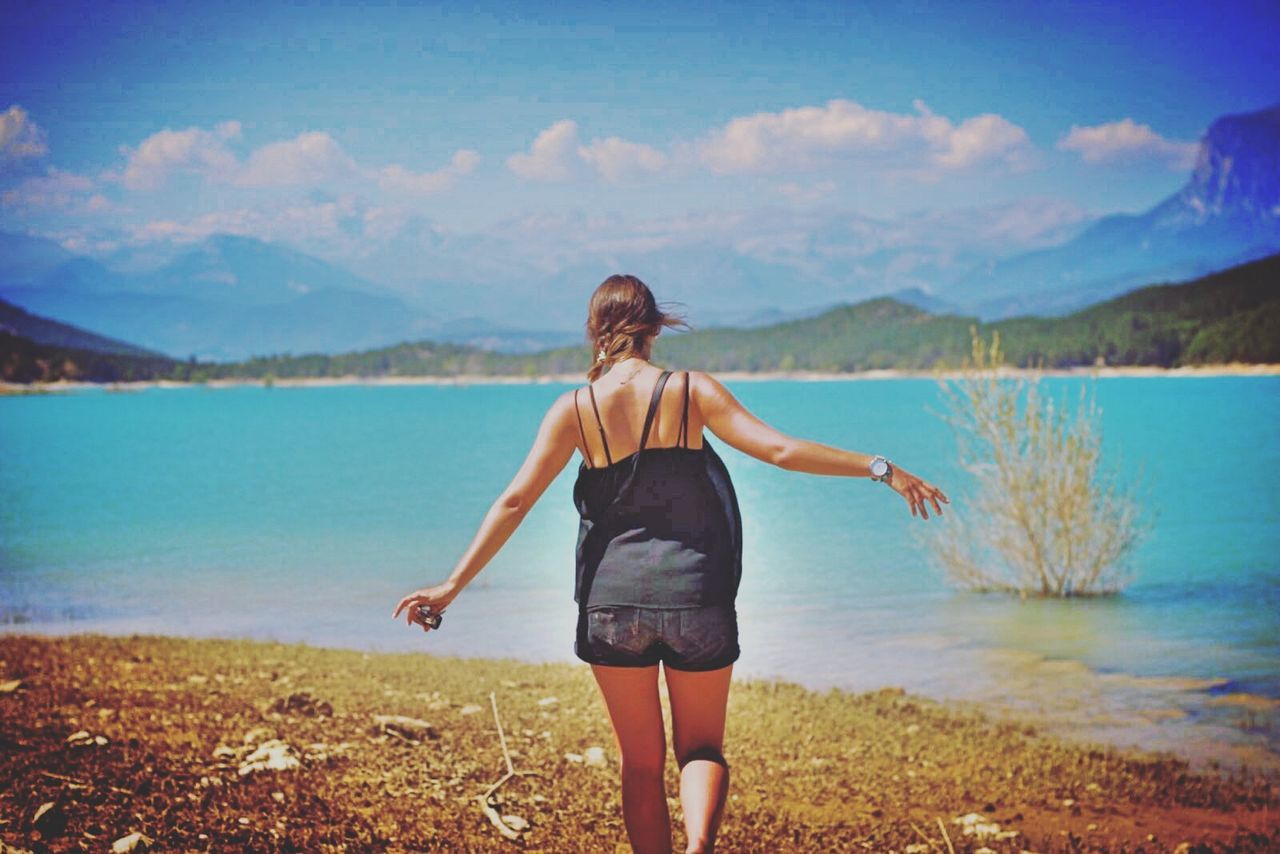 Rear view of a young woman walking by lake